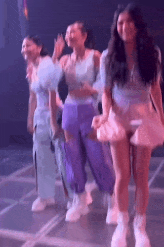 a group of women are dancing on a stage in a dark room .
