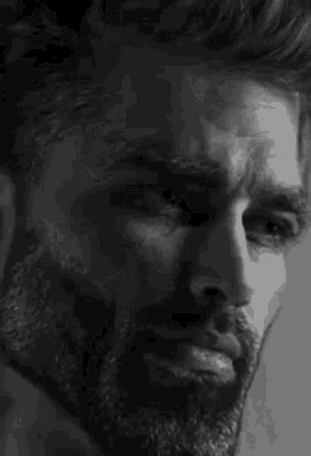 a black and white photo of a man with a beard and a serious look on his face .
