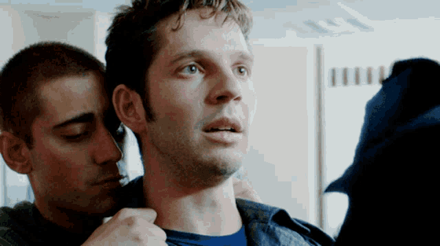 a man in a blue shirt is being held by a man in a green shirt