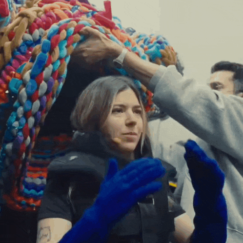 a woman wearing blue gloves and a life vest is being helped by a man