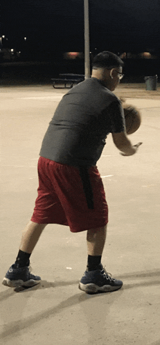 a man in red shorts is holding a basketball in his hand