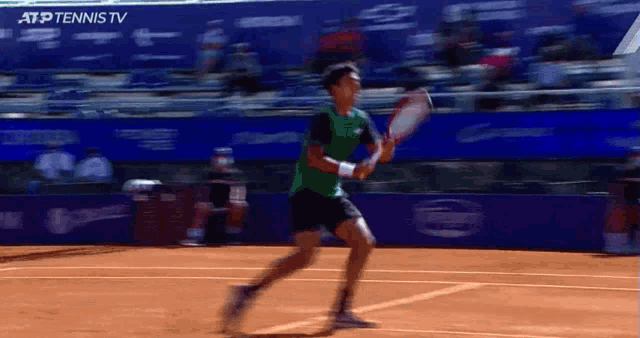 a tennis player in a green shirt is running on a tennis court