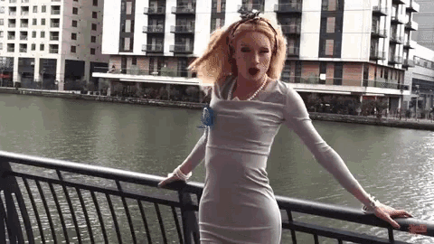 a woman in a white dress is standing on a railing near a body of water .