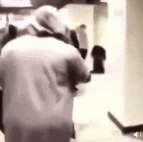 a man in a white shirt is standing in a room with a knife .