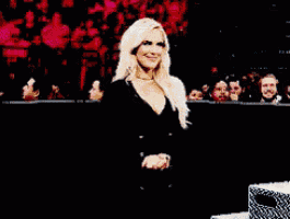 a woman in a black suit is standing in front of a crowd of people .