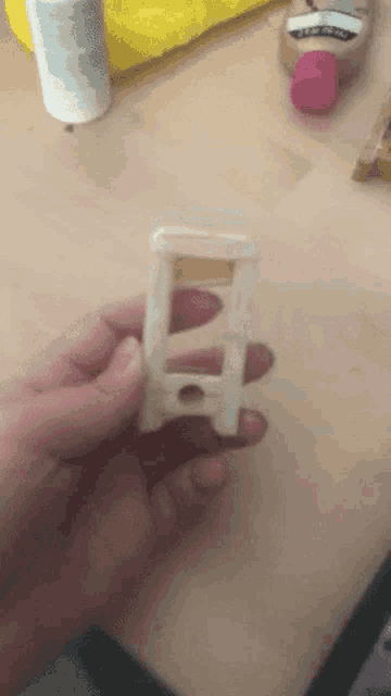 a person is holding a piece of wood with a bottle of glue behind them
