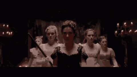 a woman in a white dress is holding a sword in a dark room .