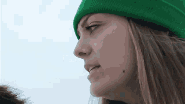 a woman wearing a green beanie is looking at something