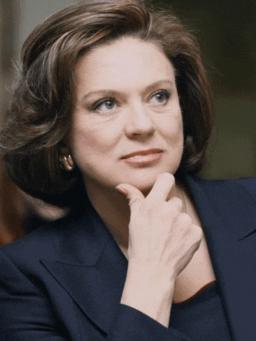 a woman with her hand on her chin and a blue jacket