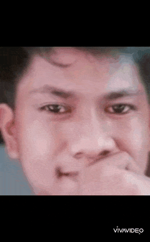 a young man is covering his mouth with his hand .
