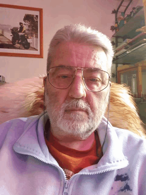 a man with glasses and a beard is sitting in front of a framed picture of a man riding a motorcycle