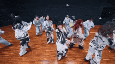a group of people are dancing in a room with a black wall