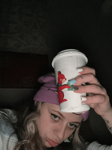 a woman holds a cup with a fox on it over her head