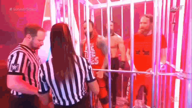 a referee is standing next to a man in a red shirt in a cage .