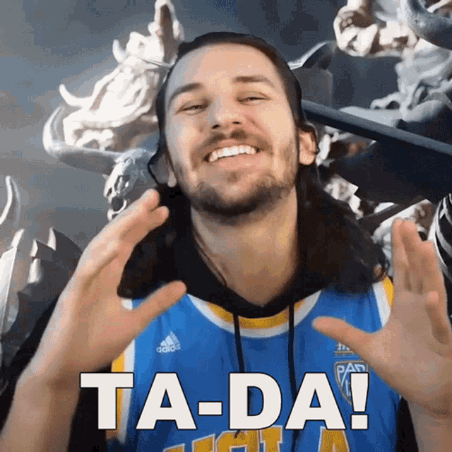 a man with a beard wearing a blue and yellow adidas jersey says ta-da