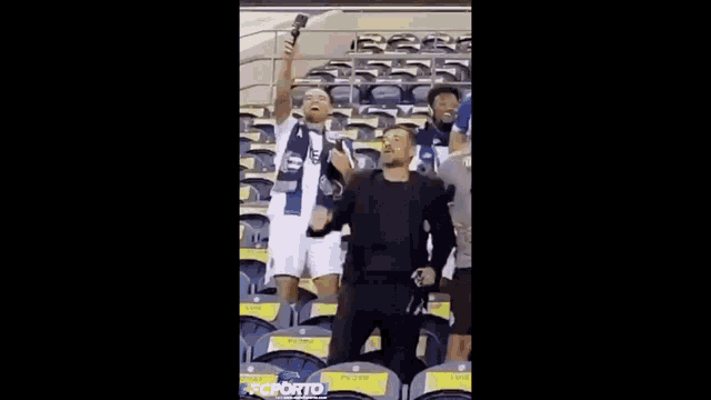 a man is holding a microphone in a stadium while sitting in a row of seats .