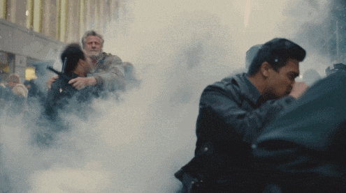 a man in a leather jacket is surrounded by smoke while another man looks on