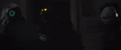 a man in a gas mask is holding a gun in a dark room