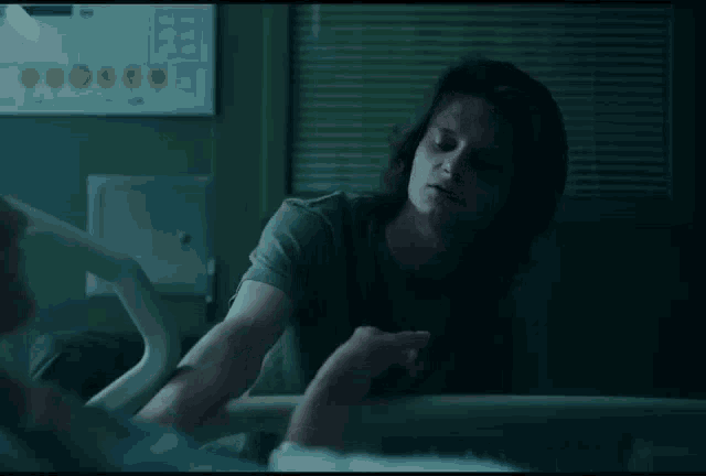 a man is sitting in a hospital bed looking at another man
