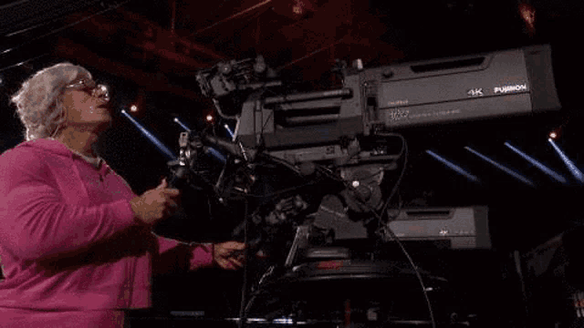 a woman is standing in front of a large camera .