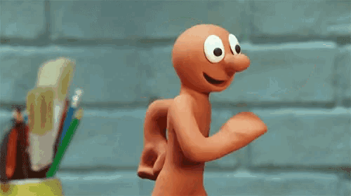 a cartoon character with big eyes is running in front of a brick wall .