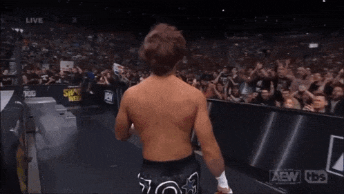 a wrestler with the number 13 on his shorts walks into a crowd