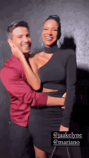 a man in a red shirt and a woman in a black dress are posing for a photo .