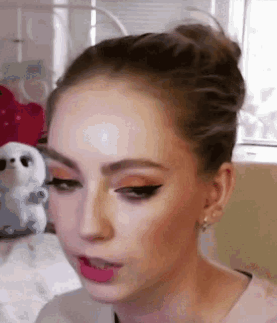 a close up of a woman 's face with a stuffed animal in the background .