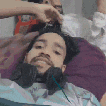 a man with headphones is laying on a bed with another man .