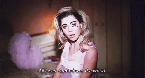 a woman is sitting on a bed with the words `` all i ever wanted was the world '' written below her .