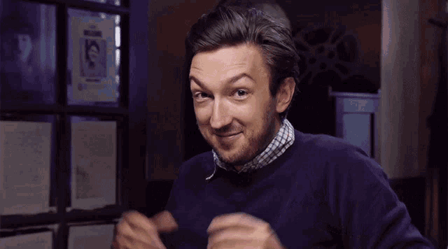 a man with a beard wearing a purple sweater and a watch