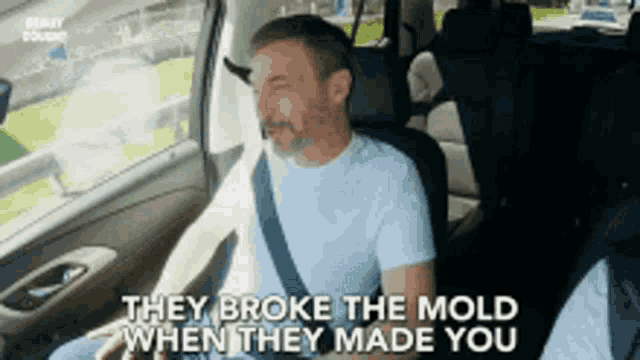 a man is sitting in the back seat of a car laughing and saying they broke the mold when they made you .