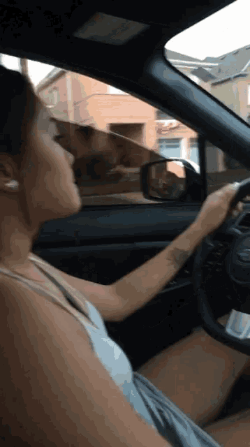a woman is driving a car in front of a building with a red arrow on it