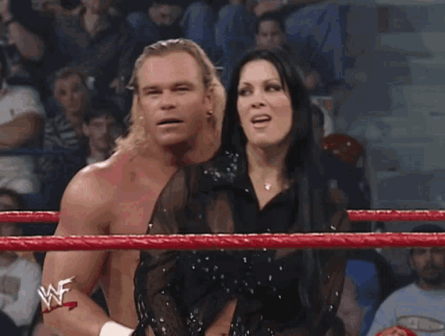 a man and a woman are in a wrestling ring with a wwe logo on their arm