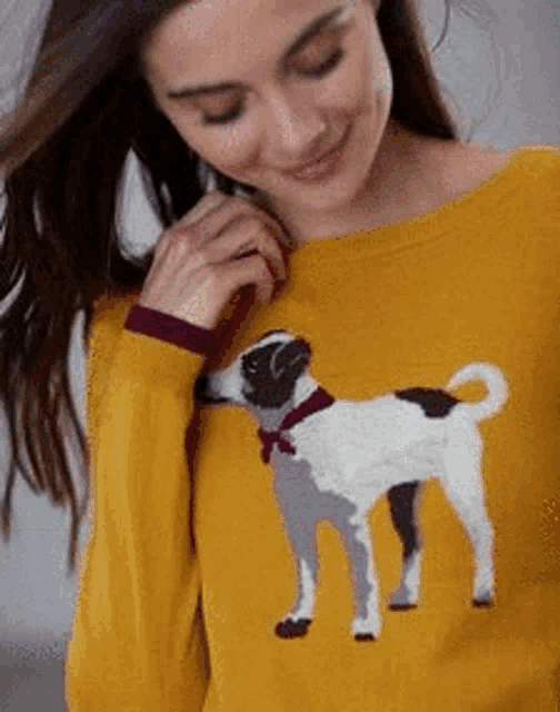 the woman is wearing a yellow sweater with a dog on it .