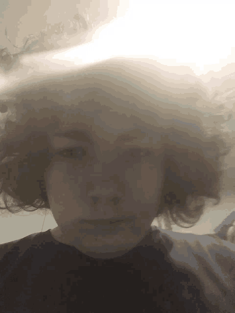 a young man with curly hair takes a selfie