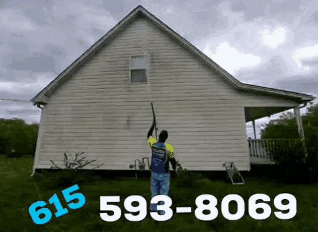 a man is cleaning the side of a house with a pressure washer .