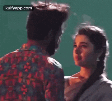 a man and a woman are looking into each other 's eyes while standing next to each other .