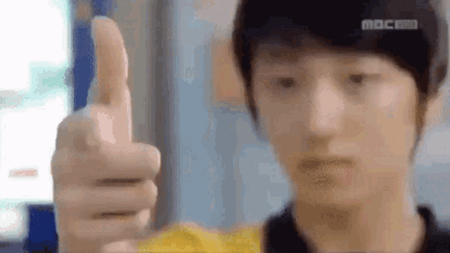 a young man is giving a thumbs up sign with his finger .