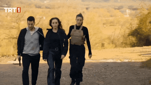 three people walking down a dirt road with trt1 on the bottom right