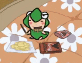 a frog is sitting on a bed next to a plate of food and a box of chocolate .