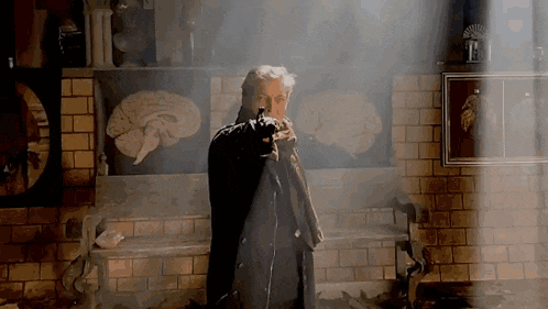 a man in a black coat is pointing a gun in front of a painting of a brain