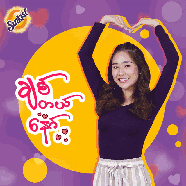 a woman making a heart shape with her hands in front of a sunkist sign