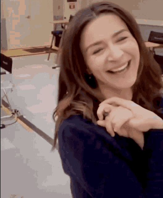 a woman is smiling with her eyes closed and her hand on her shoulder .