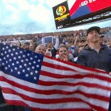a group of people holding an american flag in front of a scoreboard that says ' ed ' on it