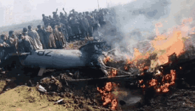 a large group of people are gathered around a burning plane with the letters zp on it