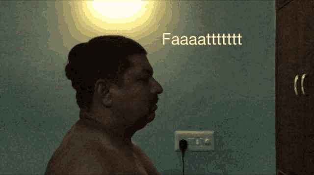 a man without a shirt is standing in front of a wall that says faaaatttttt
