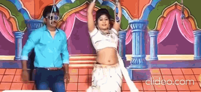 a man and a woman are dancing on a stage in front of a colorful background .