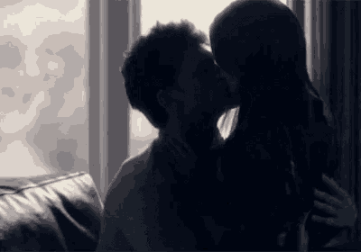 a man and a woman are kissing in front of a window in a black and white photo .