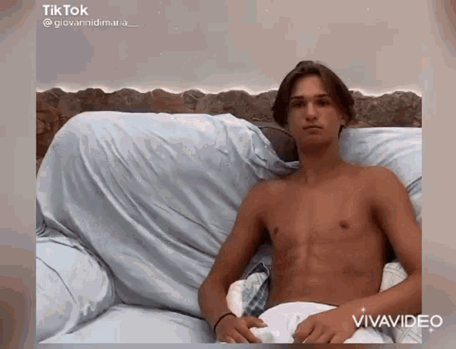 a shirtless man is sitting on a couch with a pillow .